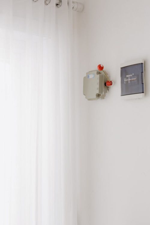 A minimalist indoor view showing an electrical circuit breaker and control panel on a white wall.